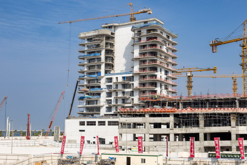 Beach Walk Iii By Imtiaz Construction site featuring a high-rise building with cranes and scaffolding against a clear blue sky.